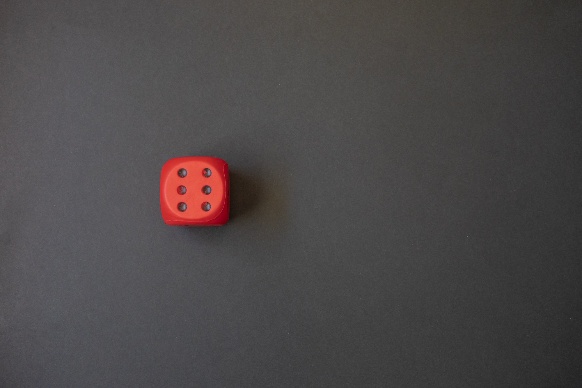 A single red die on a grey background