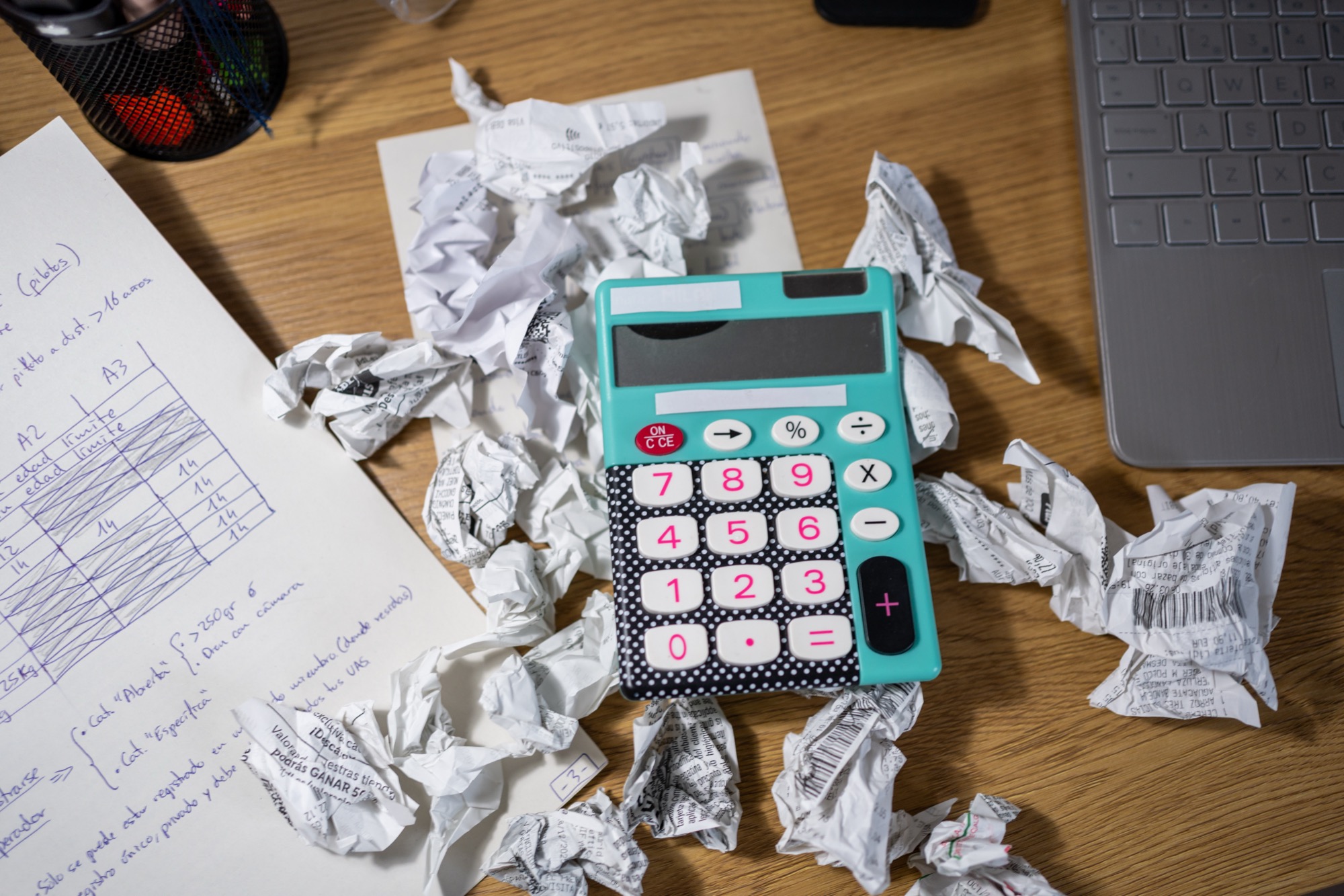 A calculator surrounded by crumpled papers on a desk, suggesting reworked calculations